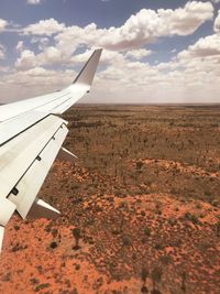 Airplane flying over landscape against sky
