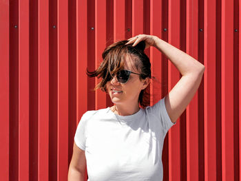 Portrait of a happy young woman in white t-shirt on red backgdrop.