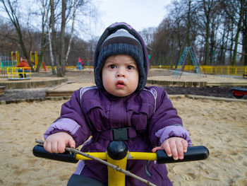 Little boy playing in the park during winter day and looking at the camera