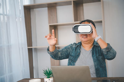 Woman gesturing while wearing virtual reality simulator at home