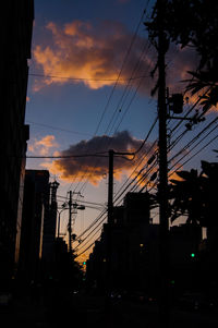 Low angle view of silhouette electricity pylon against sky during sunset