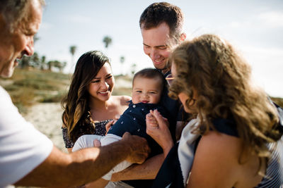 Family smiles as dad holds baby on beach