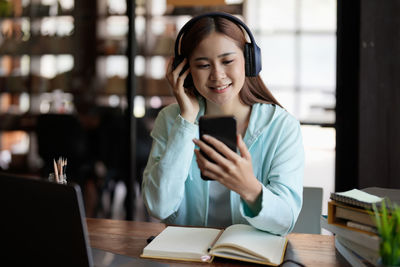 Young woman using mobile phone while sitting on table