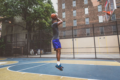 Young man practicing basketball in court