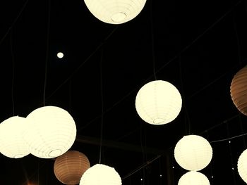 Low angle view of illuminated light bulbs hanging from ceiling