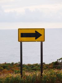 Traffic arrow sign against sea