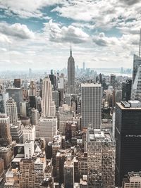 Aerial view of city buildings against cloudy sky