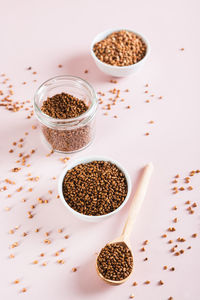 Raw buckwheat tea in a bowl and wooden spoon and buckwheat on the table vertical view