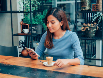 Young woman holding coffee cup on table