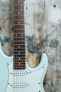 Detail of mint green electric guitar on a wood background.