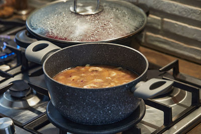 Mushrooms in sauce in saucepan on gas stove in the kitchen