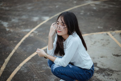 High angle view of young woman crouching on basketball court