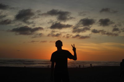 Silhouette man standing on beach against sky during sunset