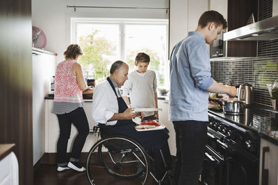 Parents and children preparing food together in kitchen