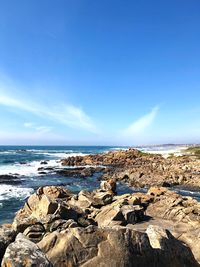 Rocks on beach against blue sky