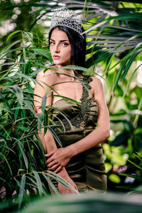 Portrait of beautiful bride wearing crown while standing amidst plants at botanical garden