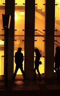 Silhouette people walking in illuminated building