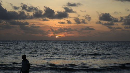 Man looking at sea against sky during sunset