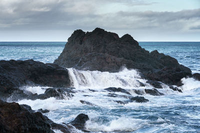 Scenic view of rocks in sea against sky