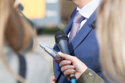 Midsection of businessman standing by microphones