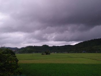 Scenic view of field against cloudy sky