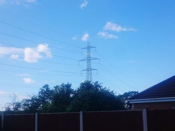 Low angle view of electricity pylon against blue sky