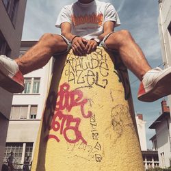 Midsection of man with text against sky in city