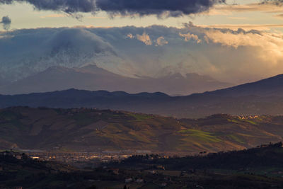 Scenic view of landscape against dramatic sky during sunset