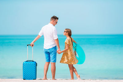 Rear view of friends on beach against sky