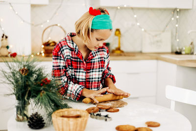 A girl in a plaid shirt bakes christmas cookies on christmas eve or new year's eve