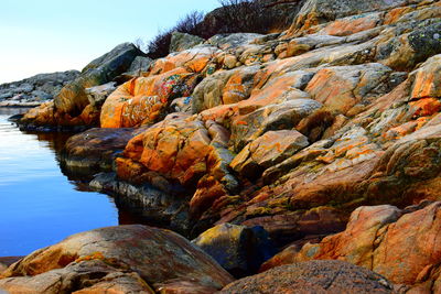 Rock formation by sea against sky