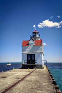 Lighthouse by sea against sky