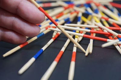 Cropped hand holding colorful sticks at table