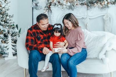 Portrait of smiling couple sitting on sofa at home