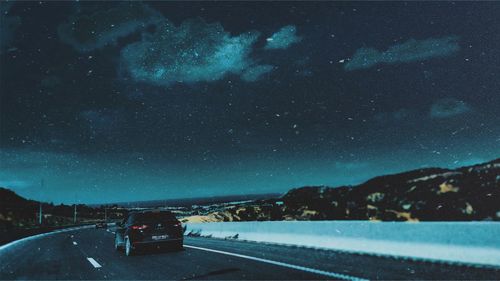 Cars on road against sky at night