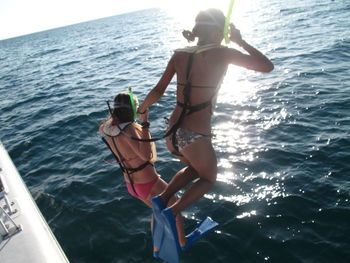 Rear view of young ladies jumping into the sea