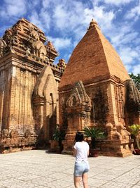 Rear view of woman standing outside temple against building