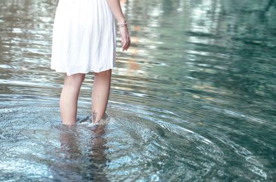 Low section of woman standing in swimming pool