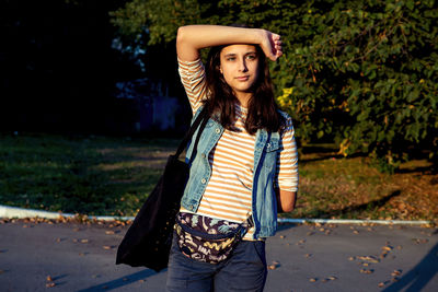 Portrait of young woman standing against trees