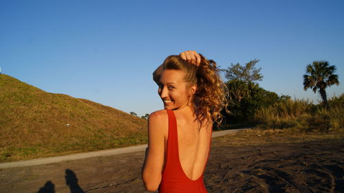 Beautiful woman standing on mountain against clear blue sky