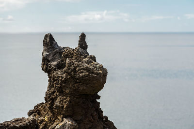 Rock formation in sea against sky