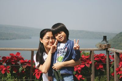 Portrait of smiling woman gesturing with son against clear sky