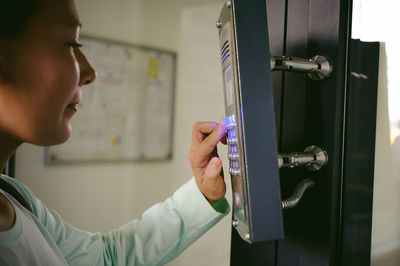 Side view of young woman using intercom