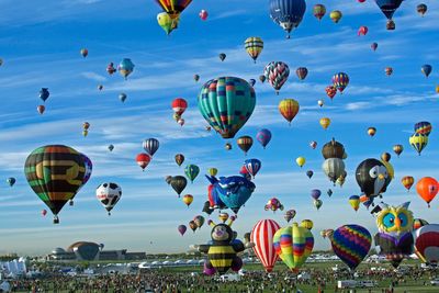 Hot air balloons flying over field against sky during festival