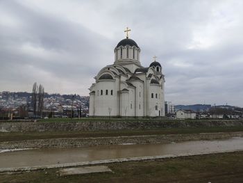 View of building by river against sky in city