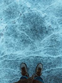 Low section of person standing by frozen water