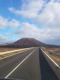 Empty road on desert against sky