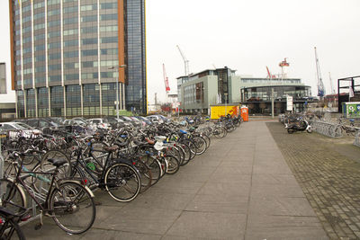 Bicycles parked on street by buildings against sky