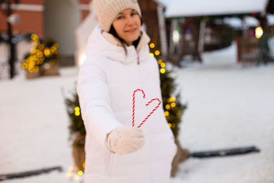 Portrait of smiling young woman standing on snow