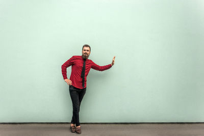 Portrait of young man standing against wall